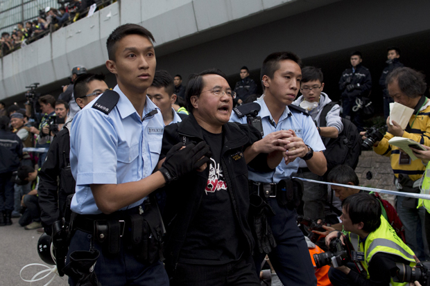 Police officers arrest a pro-democracy protester outside Hong Kong's Government complex on December 11, 2014. After more than two months and drawing crowds of over 100,000, the main Admiralty pro-democracy protest site is being cleared away by bailiffs and police after a court injunction paved the way for officials to clear three parts of the site.