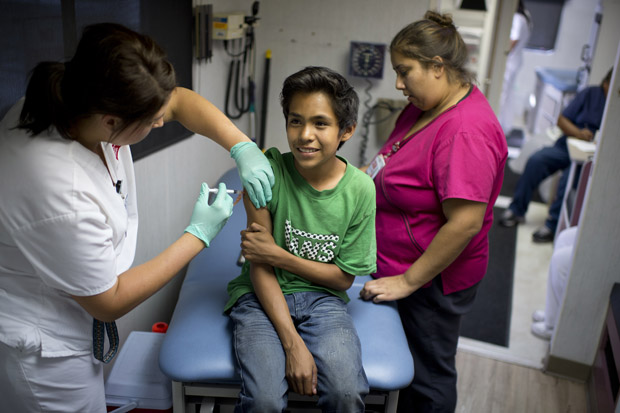 Public school student Julio Valenzuela, 11, smiles as he gets a Measles, Mumps and Rubella vaccination (MMR) at a free immunization clinic for students before the start of the school year,  in Lynwood, California.  