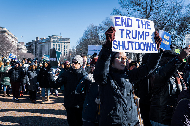 Protesters hold signs demanding an end to the government shutdown. 